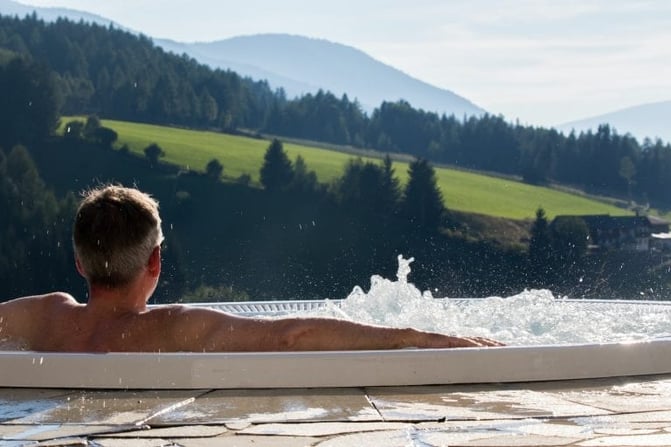 val-di-funes-september-28-man-from-behind-in-the-hot-tub-with-background-the-alpine-valley-of-the-768x512